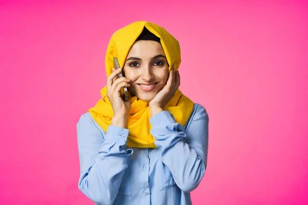 ヒジャーブ電話通信技術を身に着けているイスラム教徒の女性ピンクの背景 — ストック写真