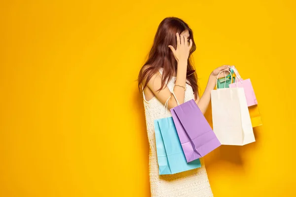 Vacker kvinna bär solglasögon poserar shopping mode gul bakgrund — Stockfoto