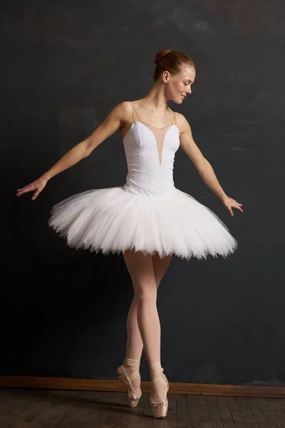 Mulher bailarina em um branco tutu dança posando desempenho fundo escuro — Fotografia de Stock