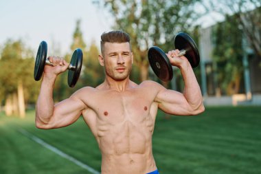 Parktaki spor egzersizinde şişirilmiş vücutlu bir sporcu.