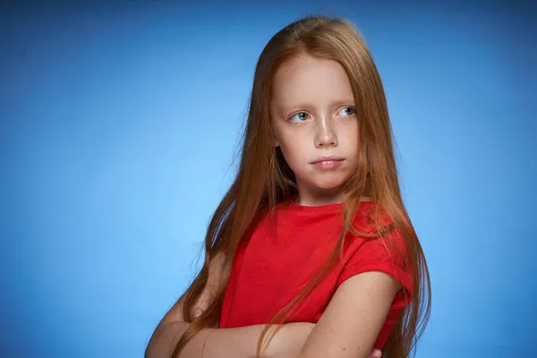 Bonito vermelho de cabelos menina no vermelho t-shirt emoções azul fundo — Fotografia de Stock