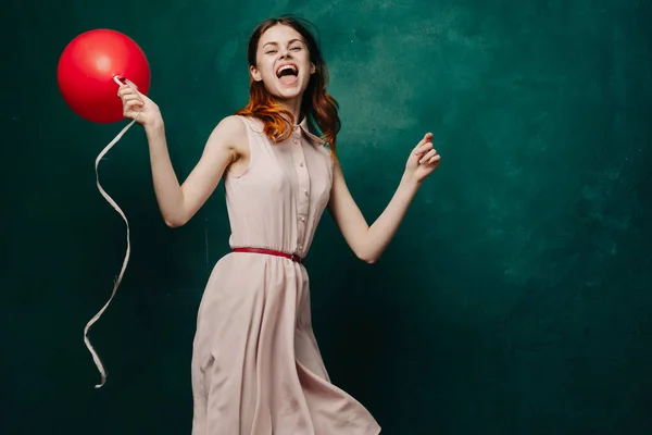 Fröhliche Frau mit rotem Ballon grünen Hintergrund Urlaub — Stockfoto