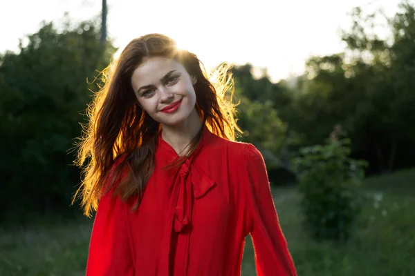 Cheerful woman in a red dress in a field outdoors fresh air Stock Image