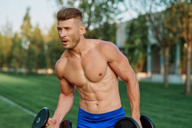 Parktaki spor egzersizinde şişirilmiş vücutlu bir sporcu.