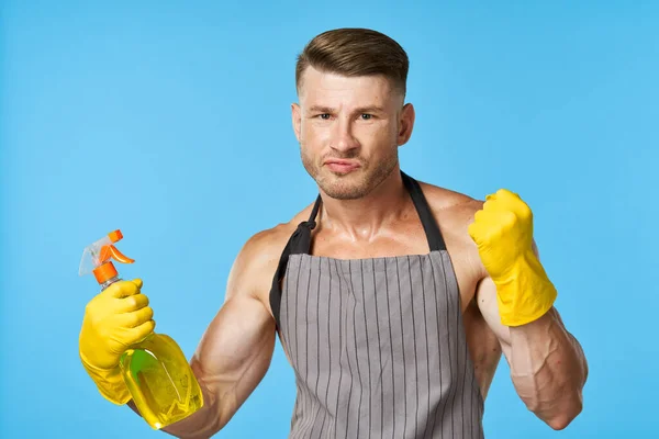 Een man met een opgepompt lichaam in schorten schoonmaakmiddel — Stockfoto