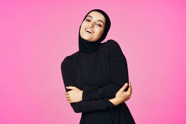 Wesoły muzułmanin kobieta w czarny hidżab pozowanie moda różowy tło — Zdjęcie stockowe