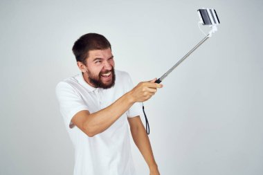 Beyaz tişörtlü adam selfie çekip eğlenceli teknoloji fotoğrafı yapıştırıyor.