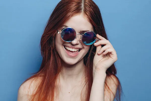 Attraktiv kvinde med bare skuldre fashionable briller blå baggrund - Stock-foto
