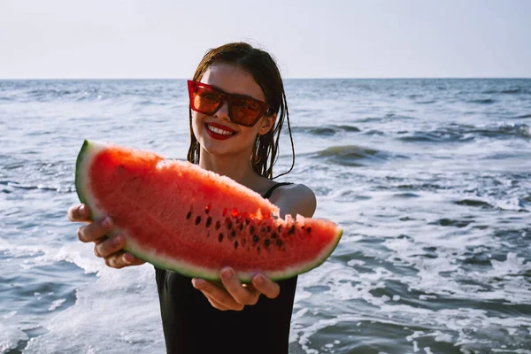 Ellerinde karpuz olan siyah mayo giymiş güzel bir kadın.