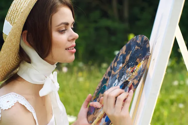 Женщина с палитрой красок рисует картину на открытом воздухе крупным планом — стоковое фото