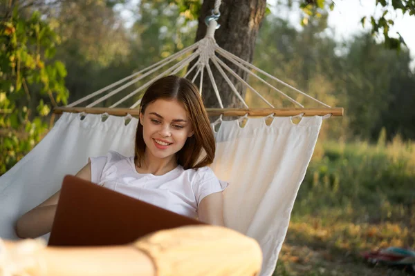 Vrolijk vrouw ligt in een hangmat met een laptop vakantie internet reizen — Stockfoto