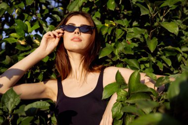 Güneş gözlükleriyle dışarıda poz veren güzel bir kadın.