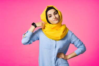 Sarı tesettürlü neşeli kadın elektronik saat teknolojisi kullanıcısı pembe arka plan