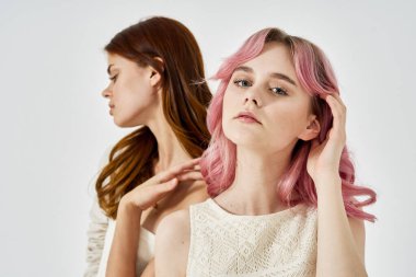 İki kız arkadaş yan yana durur. Moda cazibesi pozu verir.