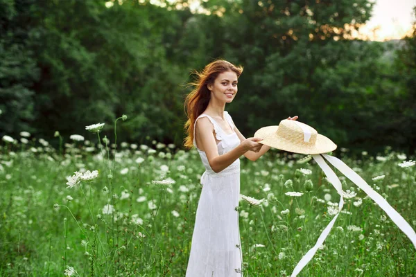 Vrouw in witte jurk hoed met bloemen natuur wandeling — Stockfoto