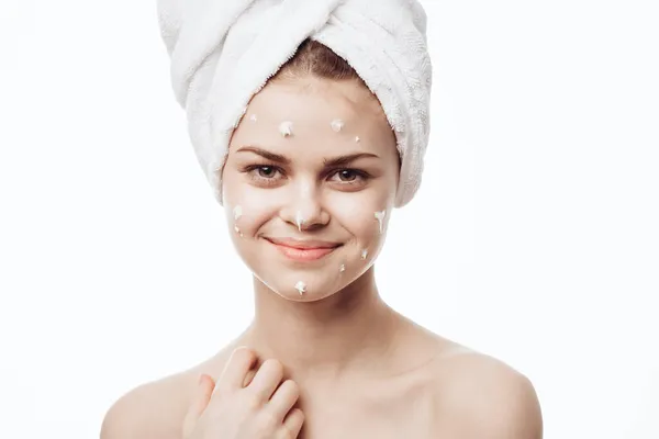 Femme gaie avec une serviette blanche sur sa tête soin de la peau crème visage — Photo