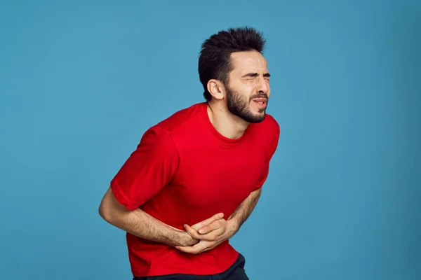 빨간 티셔츠를 입은 남성의 건강 문제 증상은 파란 배경때문에 — 스톡 사진