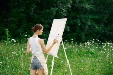 Resim paleti olan kadın ressam doğa hobisi çiziyor.