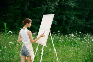 Resim paleti olan kadın ressam doğa hobisi çiziyor.