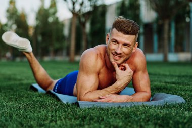 Parkta spor yapan kaslı vücutlu bir sporcu.