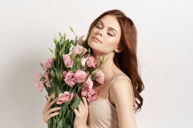Çiçeklere makyaj arkaplanı pozu veren çekici kadın.