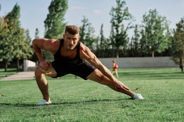 Parktaki çimlerde egzersiz yapan sporcu.