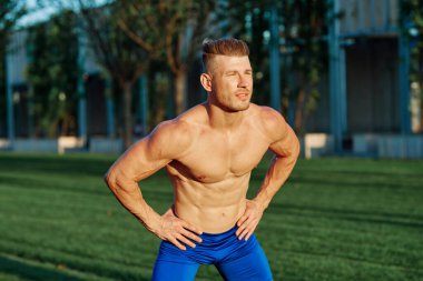 Yaz parkında egzersiz yapan kaslı bir adam.