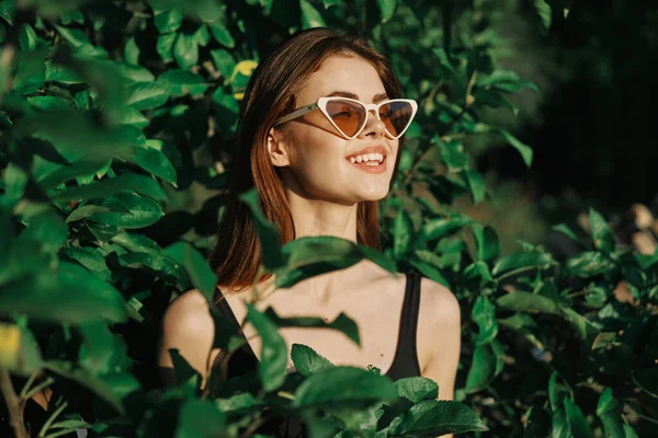 Sonriente mujer usando gafas de sol verde hojas naturaleza moda — Foto de Stock