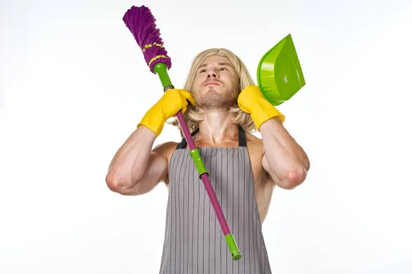 Um homem de aventais em uma peruca de mulher com uma limpeza esfregona — Fotografia de Stock