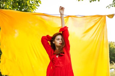 Kırmızı elbiseli güzel bir kadın elleriyle işaret ediyor doğası sarı arka planda