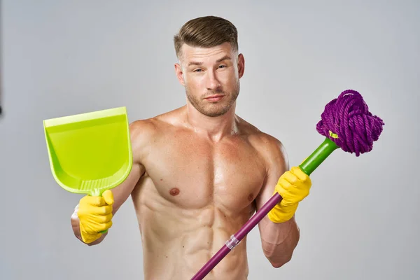 Muž ve žlutých rukavicích s nahým trupem a mopem v rukou čistí — Stock fotografie