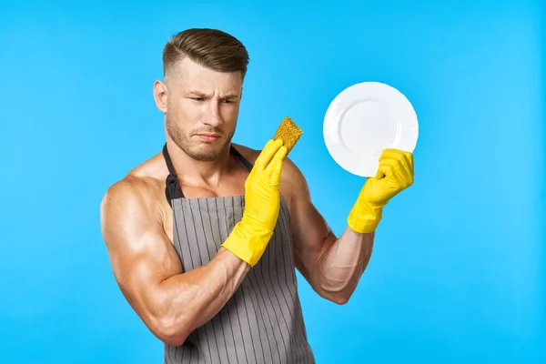 Man in apron cleaning dishwashing blue background — Stock Photo, Image