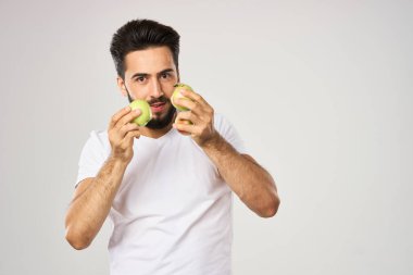 Elması beyaz tişörtlü, meyveli neşeli bir adam.