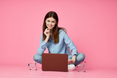 Pembe arka planda dizüstü bilgisayarı olan kadın çevrimiçi alışveriş eğlencesi