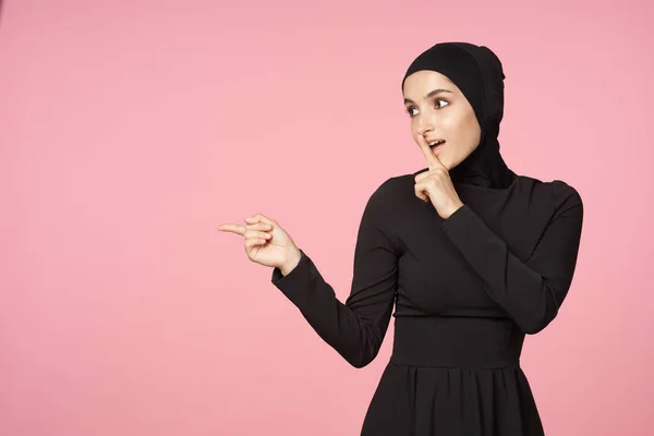 Весёлая мусульманка чёрный хиджаб позирует рукой жестом розового фона — стоковое фото
