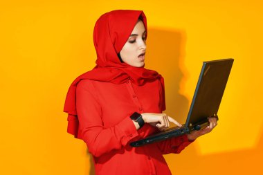 Dizüstü bilgisayarı olan neşeli bir kadın. Teknoloji duyguları sarı arka plan.