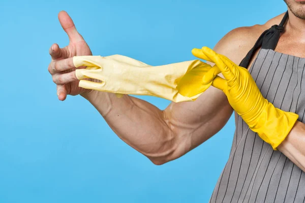 Man in schort met opgepompt lichaam rubber handschoenen schoonmaken blauwe achtergrond — Stockfoto