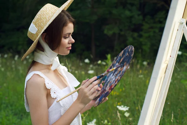 Woman with a palette of paints painting a picture outdoors close-up — Stock Photo, Image