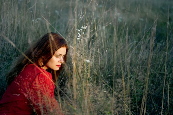 Tarladaki kadın kırmızı elbiseli çimenlerin üzerinde yatıyor. — Stok fotoğraf