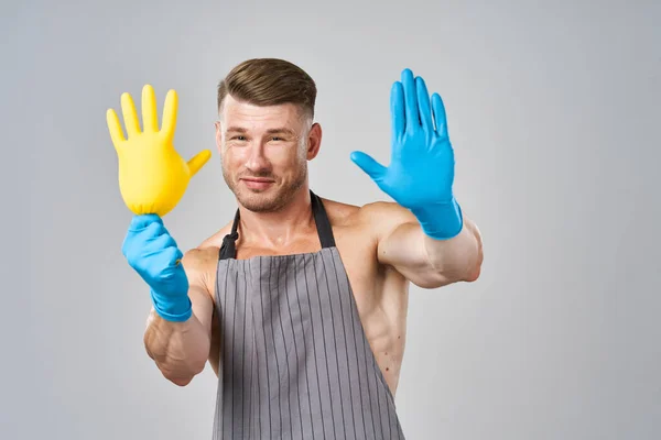 Pumped up man in apron rubber gloves cleaning housework — Stock Photo, Image