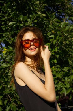 Güneş gözlüğü takan güzel kadın yeşil yapraklı yaz modeli.