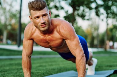 Parkta spor yapan kaslı vücutlu bir sporcu.