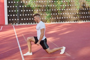Atletik erkekler yazın spor sahasında egzersiz yapıyorlar.