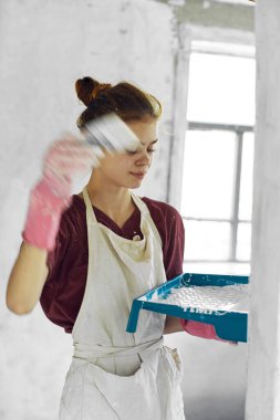 Beyaz önlüklü ev dekorasyonu yapan kadın ressam.