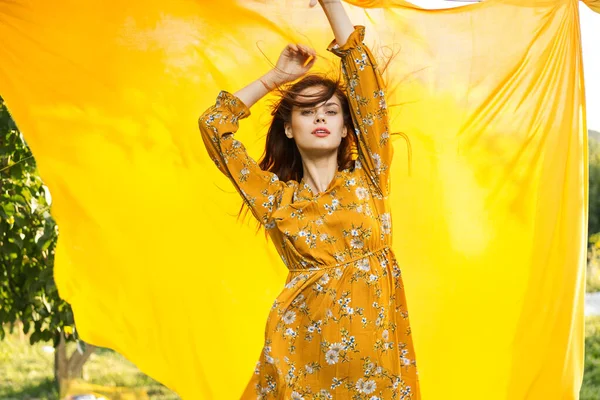 Leende kvinna i gul klänning poserar natur gul duk — Stockfoto