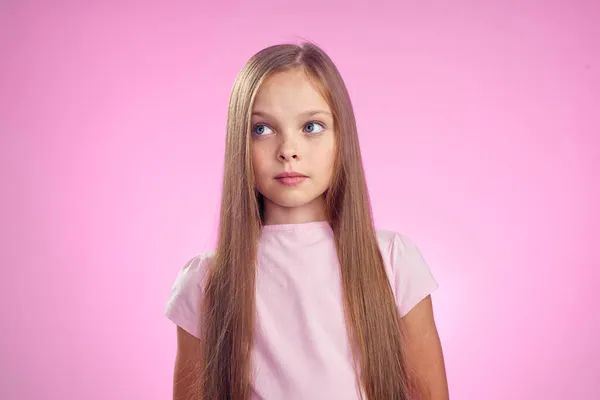 Ragazza carina con i capelli lunghi su sfondo rosa stile di vita infanzia — Foto Stock