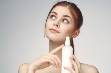 Çıplak omuzlu bir kadın cilt bakım kremi kullanıyor.
