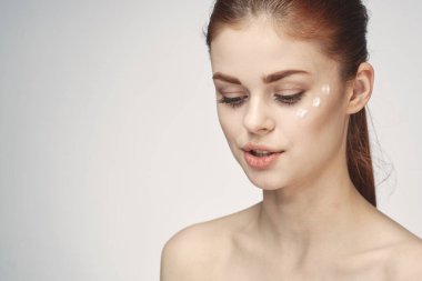 Çıplak omuzlu kadın yüz kremi cilt bakımına yakın çekim