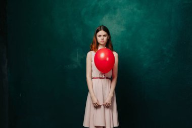 Kırmızı balonlu kadın yeşil arka planda tatil eğlencesi