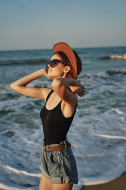 Kumsalda yürüyen bir kadın, tatil güneşinde seyahat ediyor.